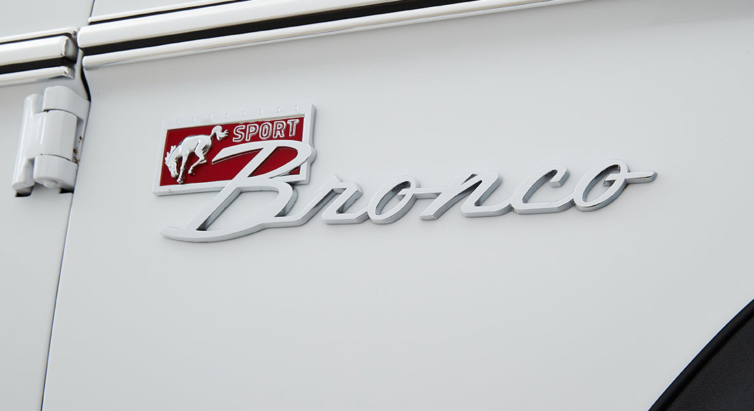 White Classic Ford Bronco exterior with chrome Sport Bronco emblem and red horse logo