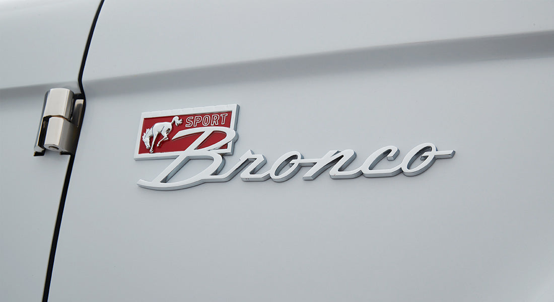 Chrome Classic Ford Bronco emblem with red background and sport lettering on white door