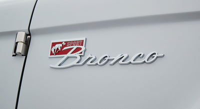 Chrome Classic Ford Bronco emblem with red background and sport lettering on white door