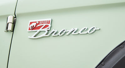 Classic Ford Bronco logo badge showing a running horse with a red and white background on mint green paint.