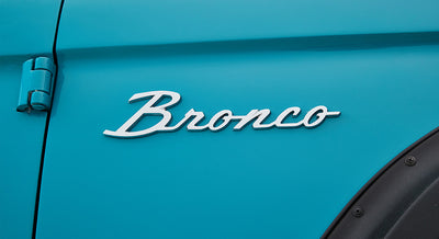 Blue Classic Ford Bronco with silver Bronco emblem on the vehicle side panel