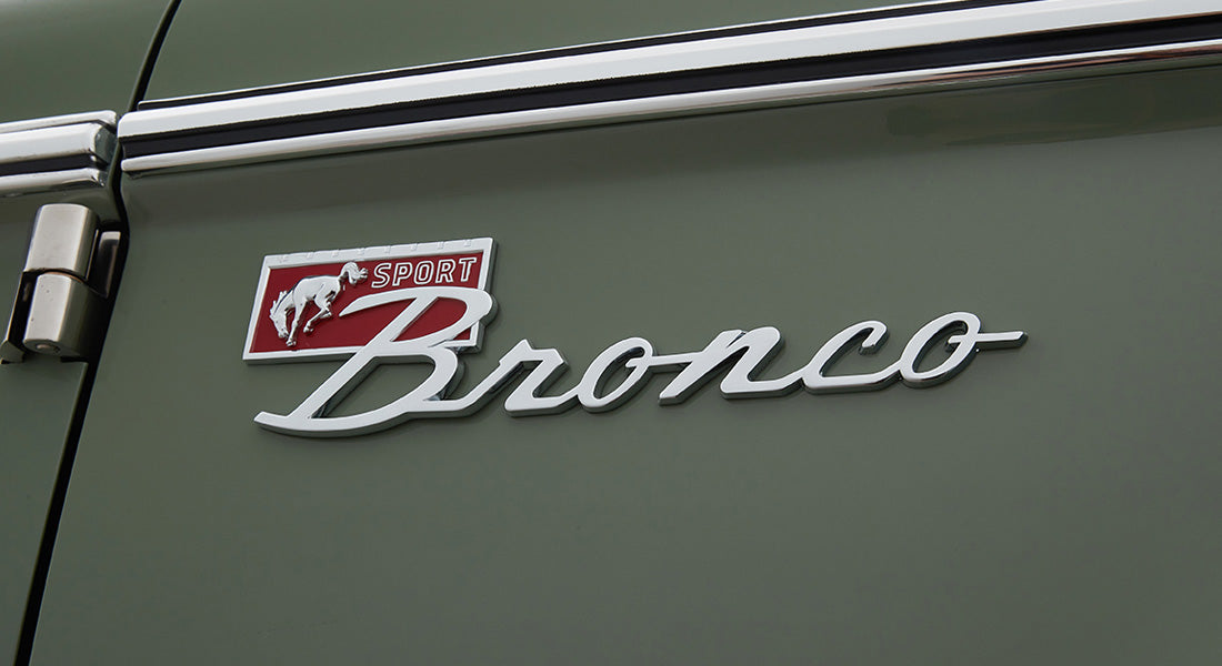 Chrome Classic Ford Bronco emblem with red 'Sport' badge on green vehicle body