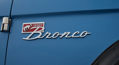 Chrome Classic Ford Bronco emblem and 'Sport' badge on blue exterior door panel.