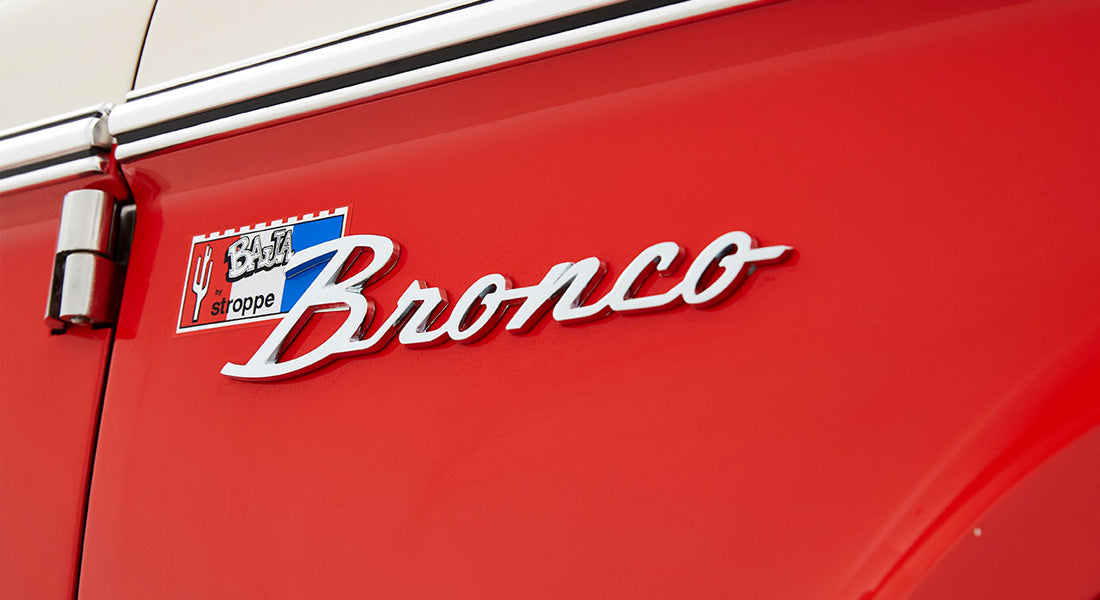 Red Classic Ford Bronco with ‘Baja by Stropping’ emblem on the side door