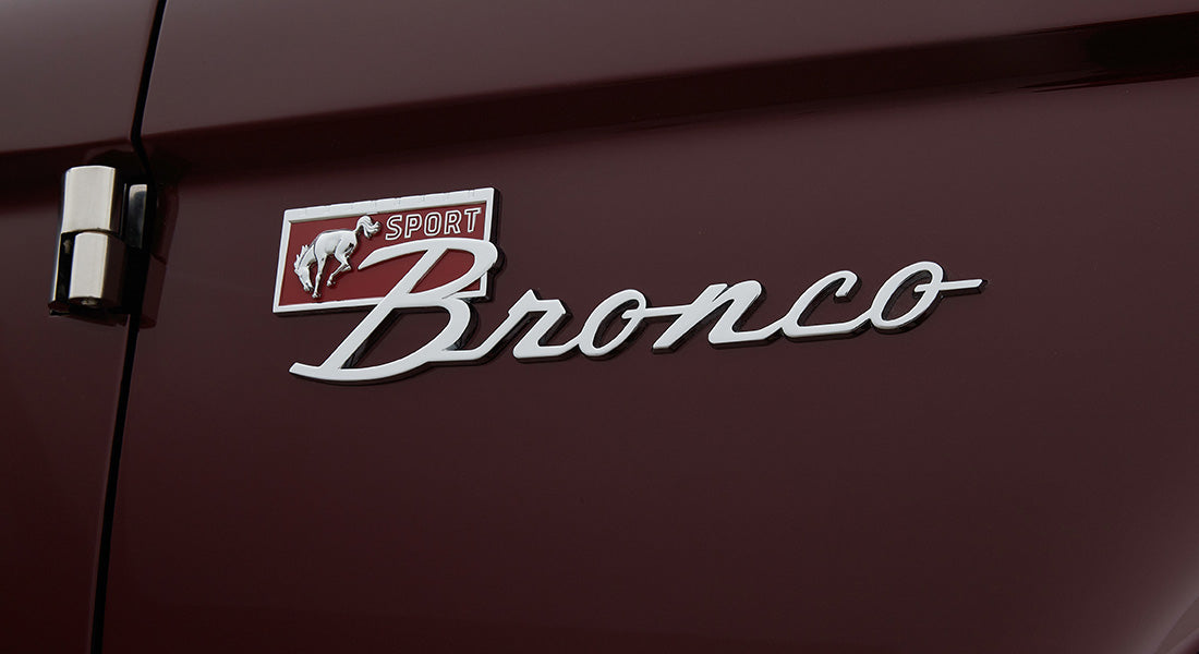 Classic Ford Bronco sport emblem on dark red exterior door panel