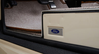 Door sill area with Ford emblem mounted on cream-colored frame