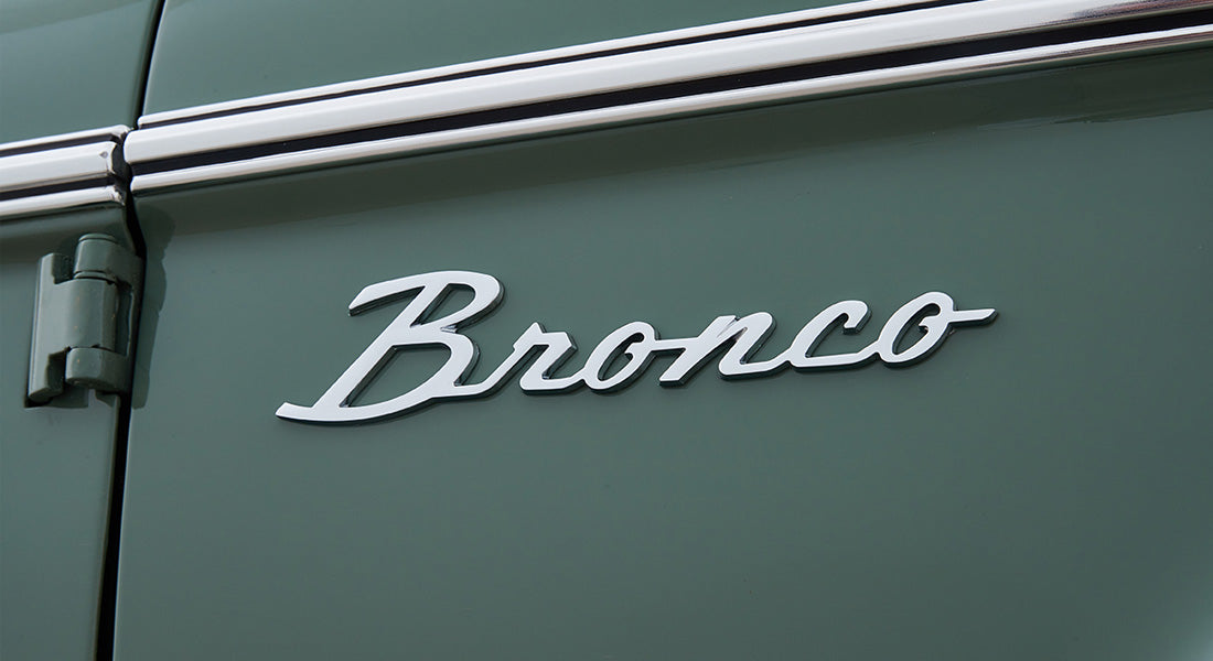 Chrome 'Bronco' emblem on green painted exterior panel of Classic Ford Bronco