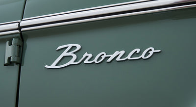 Chrome 'Bronco' emblem on green painted exterior panel of Classic Ford Bronco