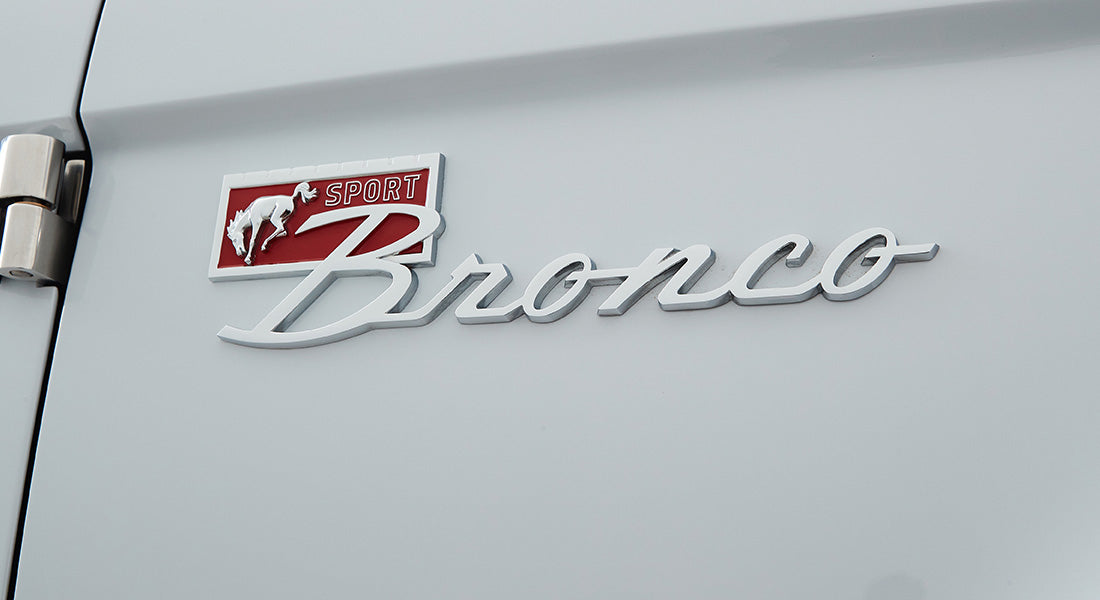 Chrome Sport Bronco emblem on white painted exterior of a Classic Ford Bronco.