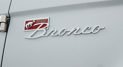 Chrome Sport Bronco emblem on white painted exterior of a Classic Ford Bronco.