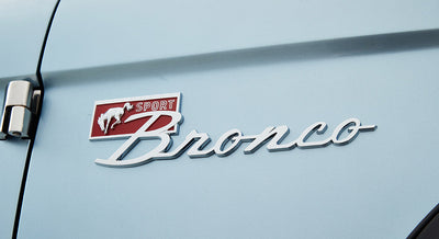 Chrome Sport Bronco emblem on light blue exterior body of Classic Ford Bronco