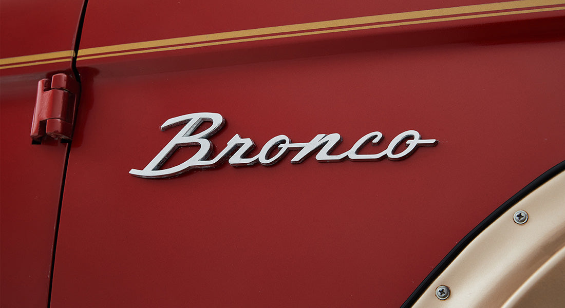 Red vehicle exterior with raised chrome Bronco emblem near door hinge
