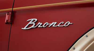 Red vehicle exterior with raised chrome Bronco emblem near door hinge