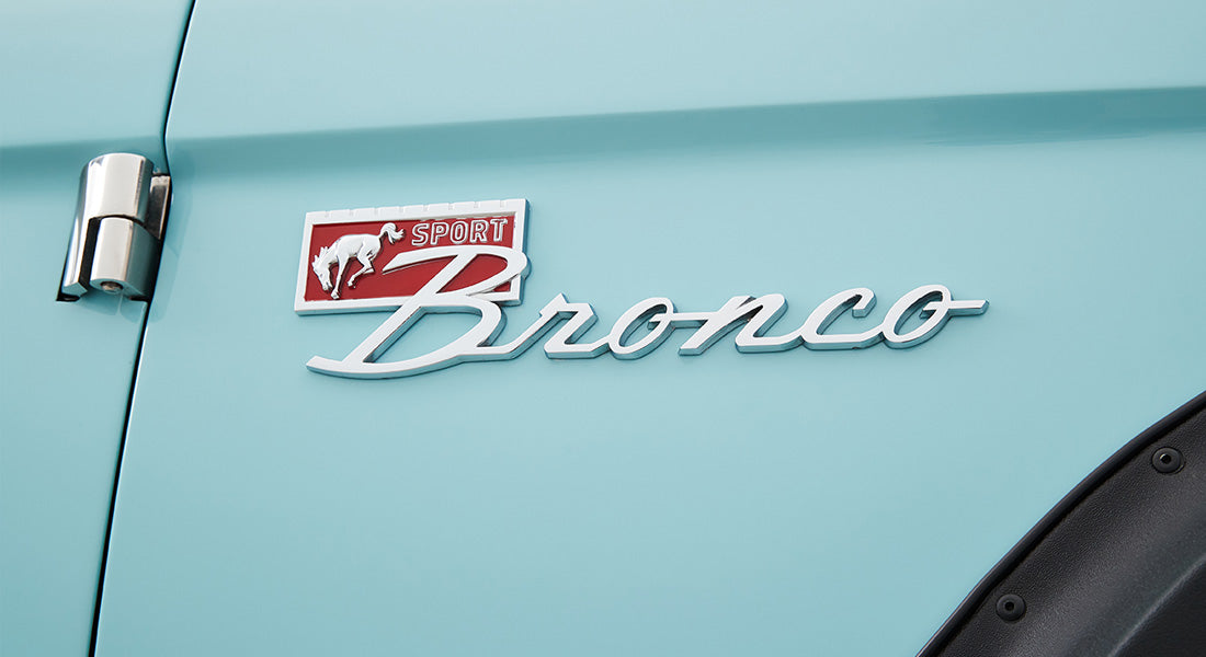 Classic Ford Bronco emblem on light blue vehicle door