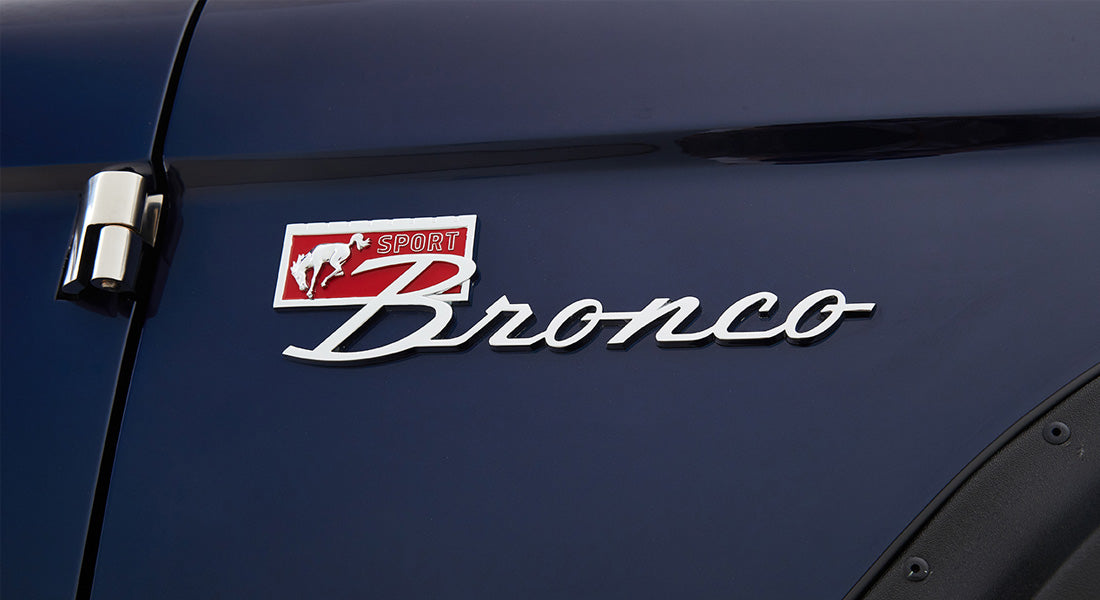 Side emblem on dark blue vehicle door reading Sport Bronco with a red and white horse logo