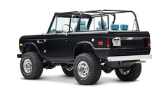 Rear three-quarter view of black Classic Ford Bronco with roll cage and plaid seats