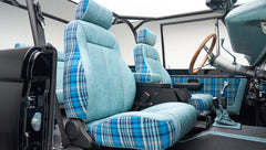 Front seats inside Classic Ford Bronco with blue plaid upholstery and roll cage