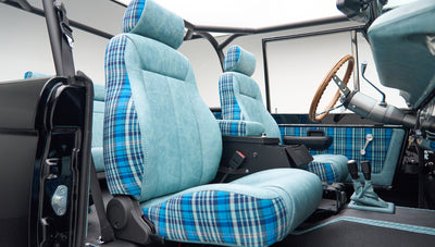 Front seats inside Classic Ford Bronco with blue plaid upholstery and roll cage