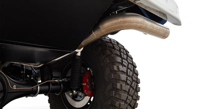Underbody view of a tire with a red brake caliper and a stainless steel exhaust pipe