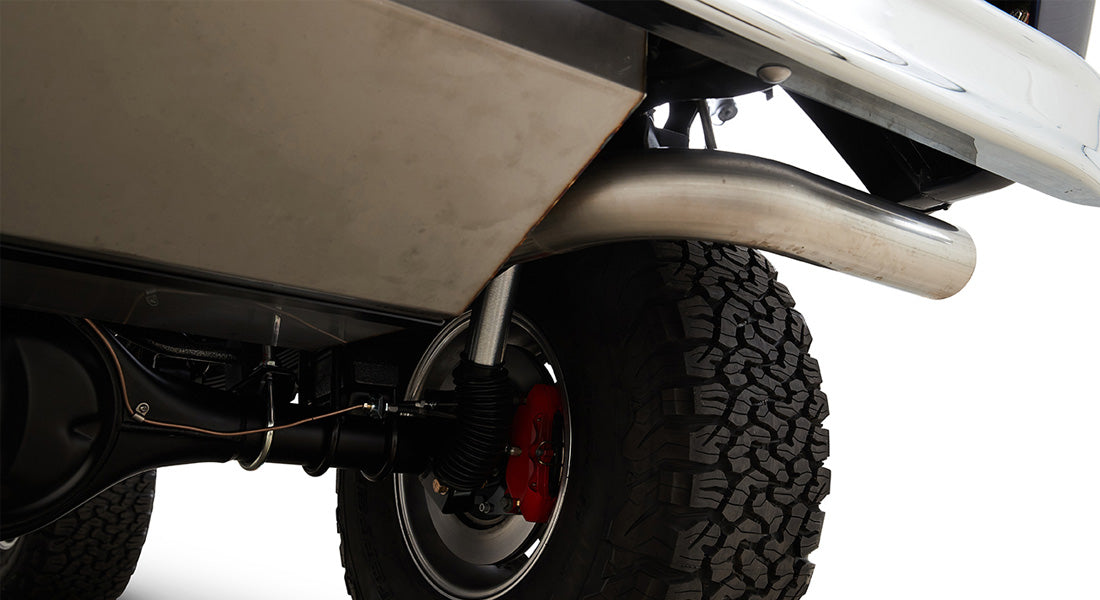 Rear suspension view with red brake caliper, exhaust pipe, and large off-road tire
