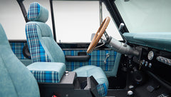 Front seats and wooden steering wheel inside Classic Ford Bronco with plaid accents