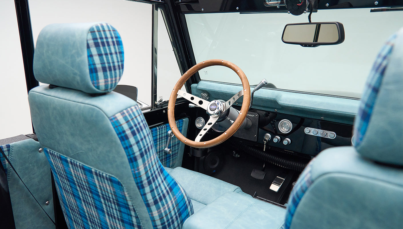 Interior front seats and dashboard with wooden steering wheel inside Classic Ford Bronco