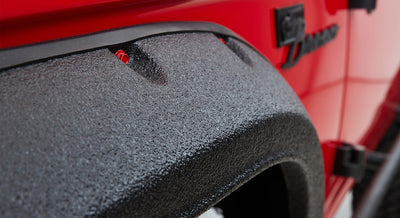 Textured black fender flare on red Classic Ford Bronco body near the wheel well edge