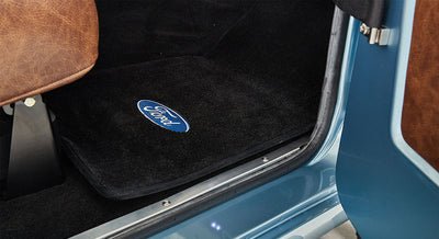 Black floor mat with blue oval Ford logo inside a Classic Ford Bronco