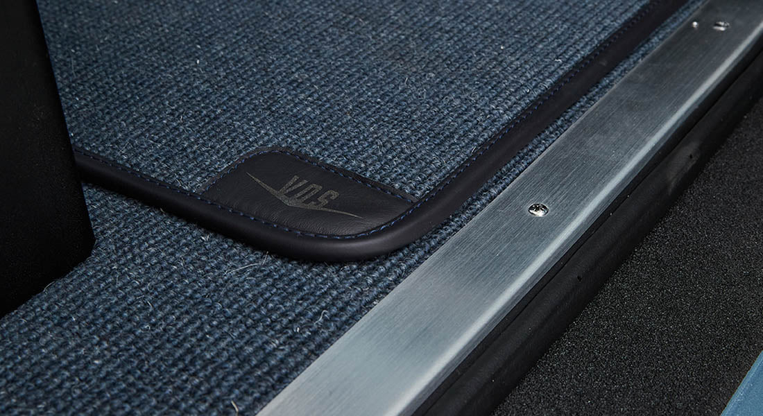 Blue textured floormat with leather trimmed corner inside a Classic Ford Bronco