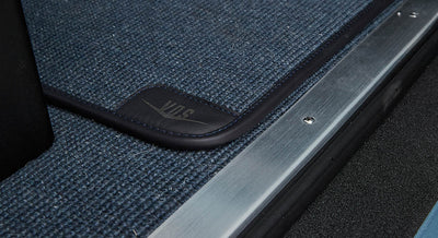 Blue textured floormat with leather trimmed corner inside a Classic Ford Bronco