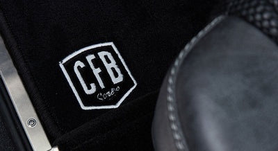 Black floor mat with CFB Series logo partially under Classic Ford Bronco seat
