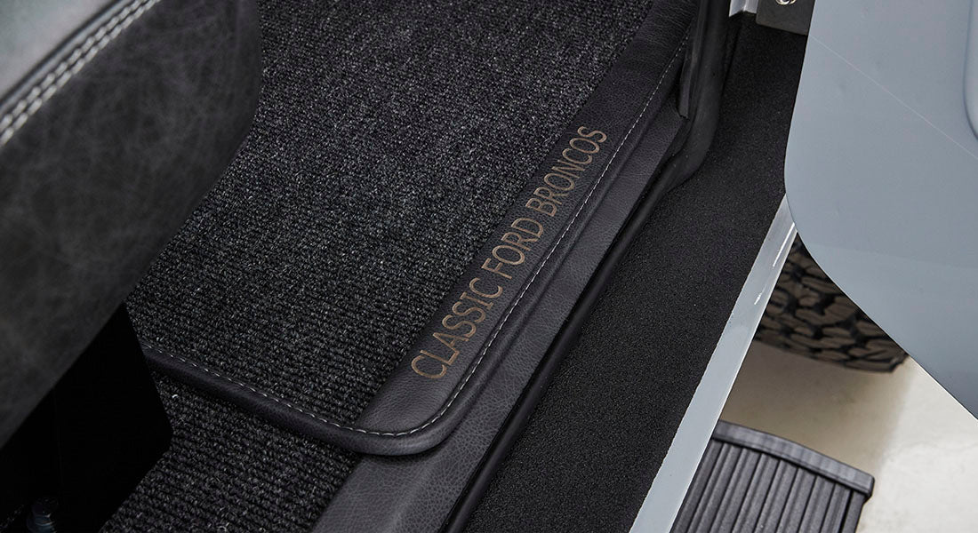 Interior floormat with 'CLASSIC FORD BRONCOS' text visible on dark carpeted surface