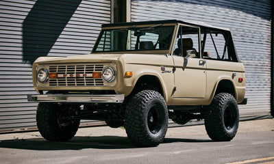 Three-quarter rear view of Classic Ford Bronco 1971 Quicksand color parked in front of brick wall