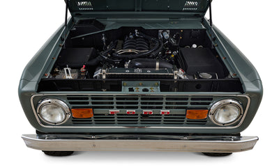 Engine compartment of a marble gray Classic Ford Bronco with visible engine components