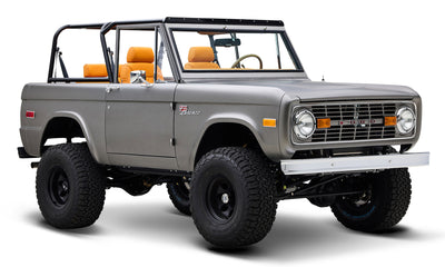 Classic Ford Bronco in matte silver side view with raised suspension and black wheels