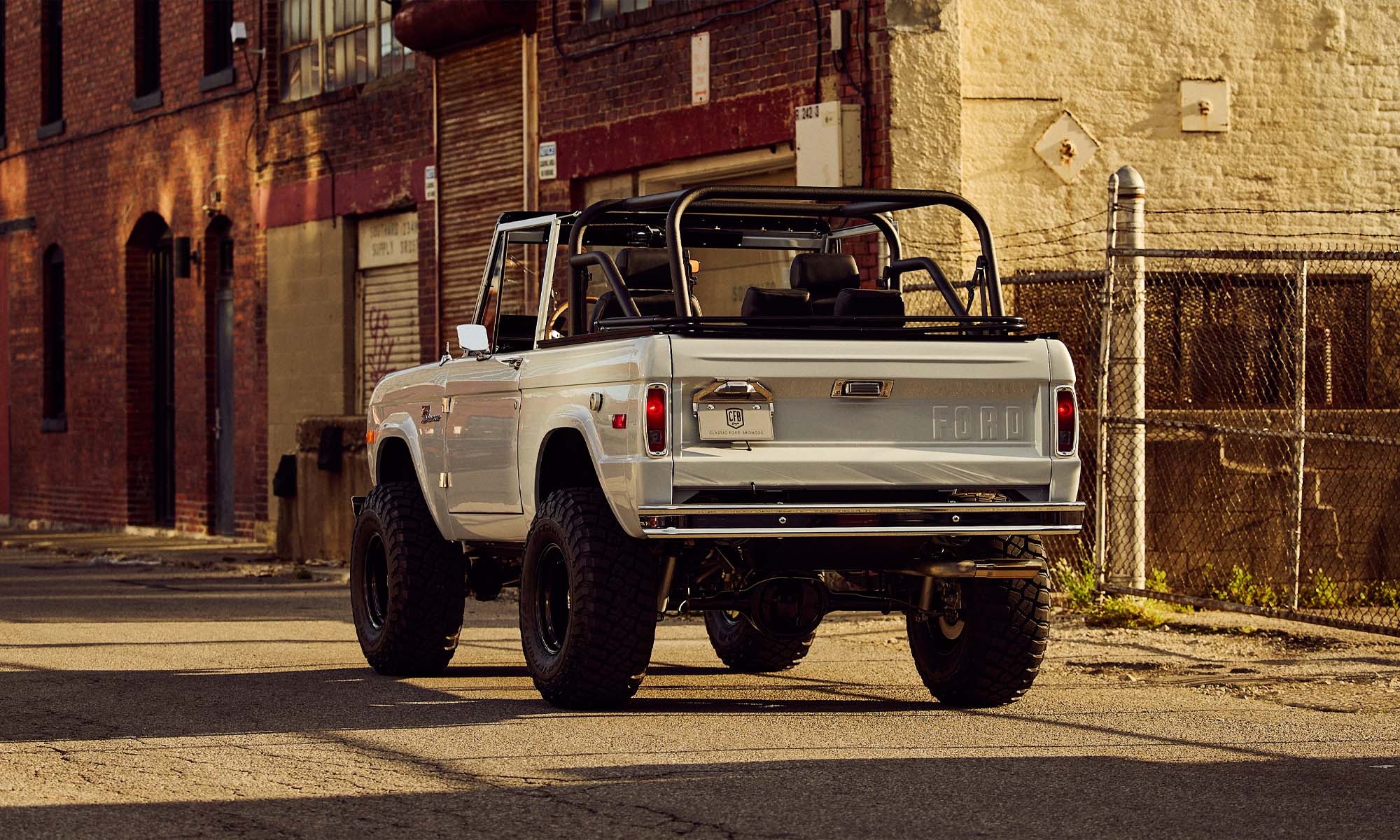 Classic Ford Bronco in white with tan soft top seen from driver rear angled view