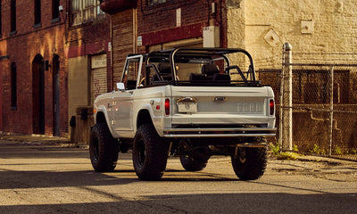 Classic Ford Bronco in white with tan soft top seen from driver rear angled view