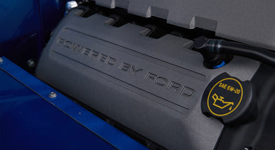 Close-up of engine cover embossed with 'Powered By Ford' and oil cap