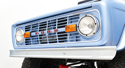 Front grille and headlights of a light blue Classic Ford Bronco with FORD lettering