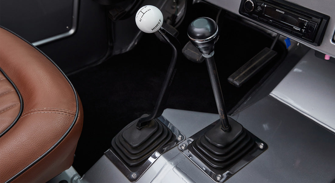 Two shifter levers inside a Classic Ford Bronco with manual gear shift ball labeled Hurst