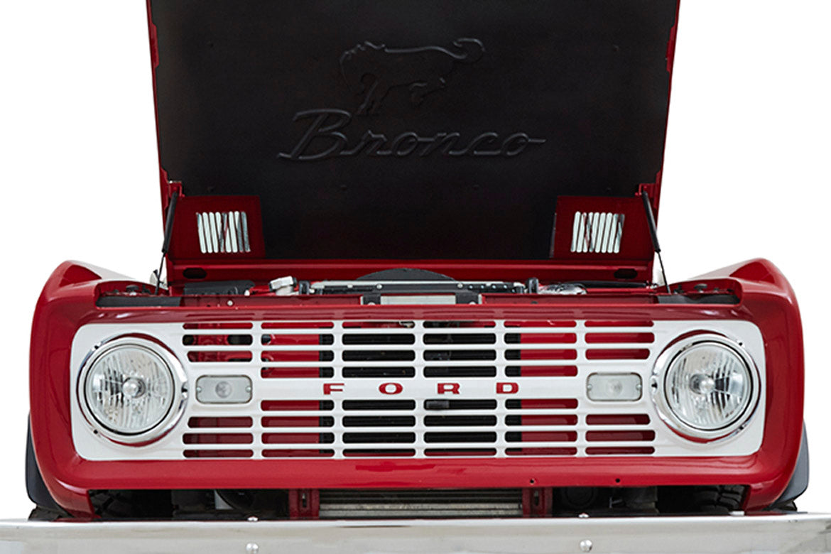 Front grille and headlights of red Classic Ford Bronco with hood open