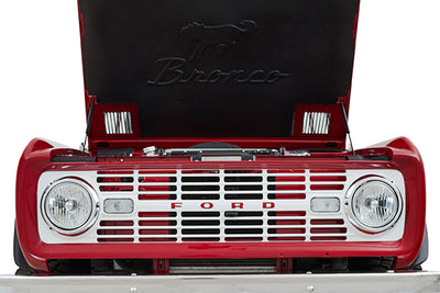 Front grille and headlights of red Classic Ford Bronco with hood open