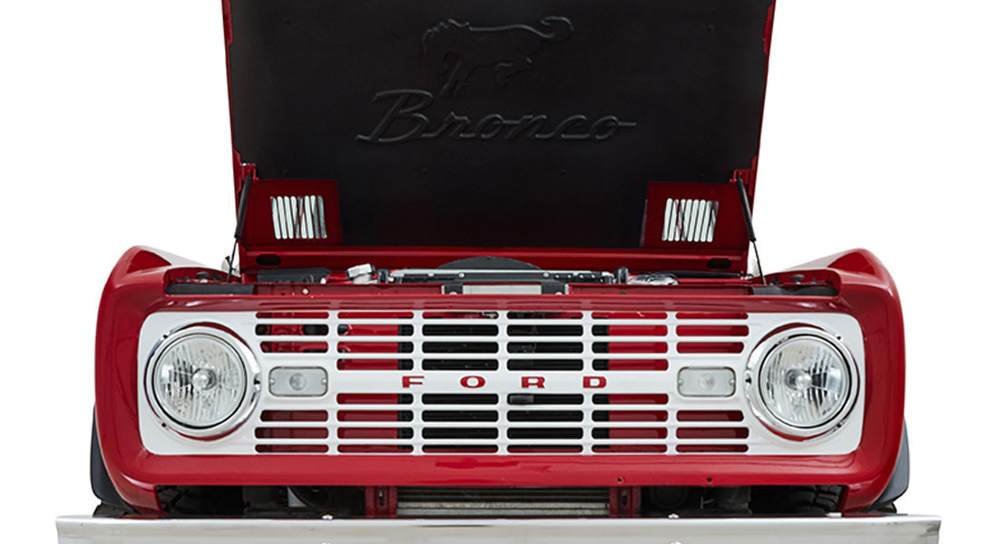 Front grille and headlights of red Classic Ford Bronco with hood raised