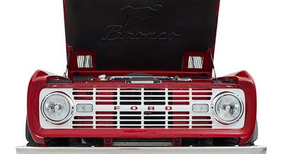 Front grille and headlights of red Classic Ford Bronco with hood raised
