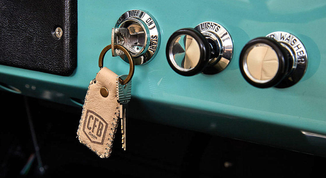 Ignition key with leather keychain hanging from ignition switch on turquoise dashboard