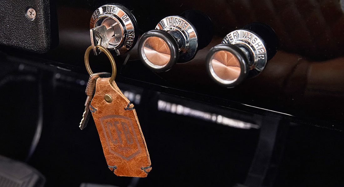 Car ignition switch with leather key fob and dashboard knobs labeled lights and wiper washer
