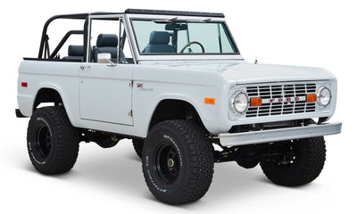 White Classic Ford Bronco with black roll cage and blue seats on white background