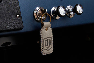 Leather keychain with CFB Series logo hanging from a classic vehicle ignition switch