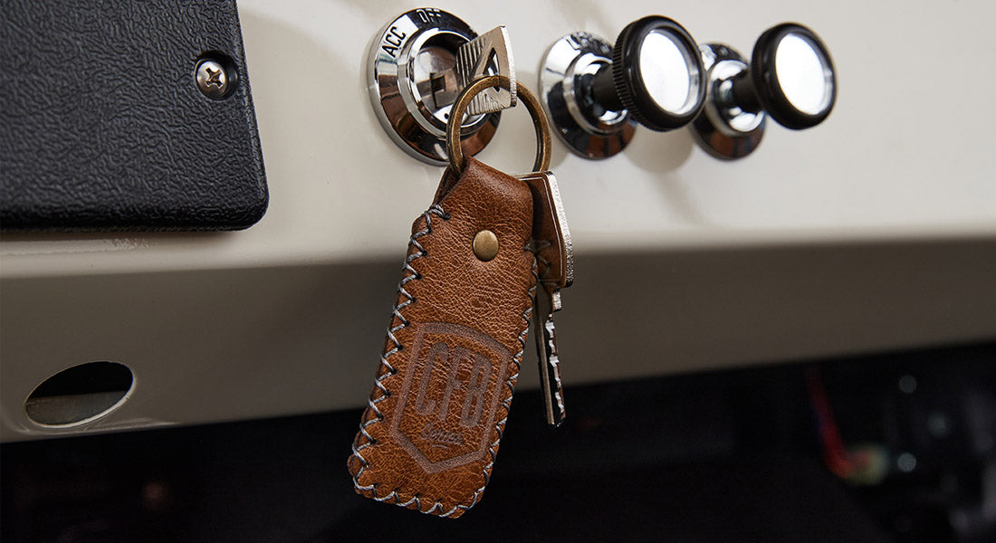 Car key inserted in ignition with brown leather keychain featuring CFB logo