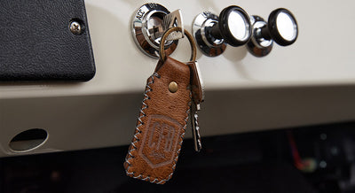 Car key inserted in ignition with brown leather keychain featuring CFB logo